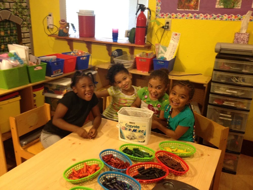Four children sitting at a table with craft supplies
