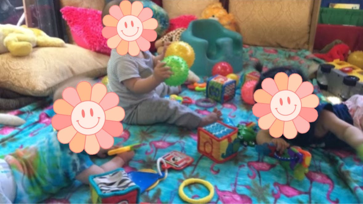 Three children playing with toys on a patterned blanket