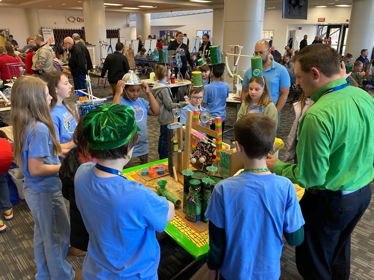 Adults and children gathered around a table with a science project