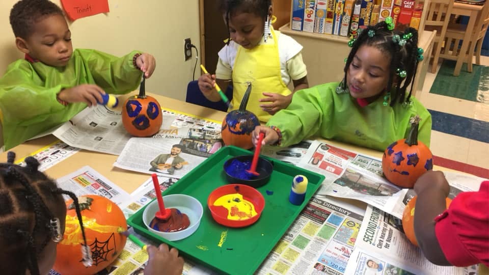 Children painting pumpkins at a table