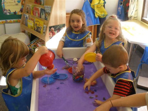 Children playing with water and toys in a classroom