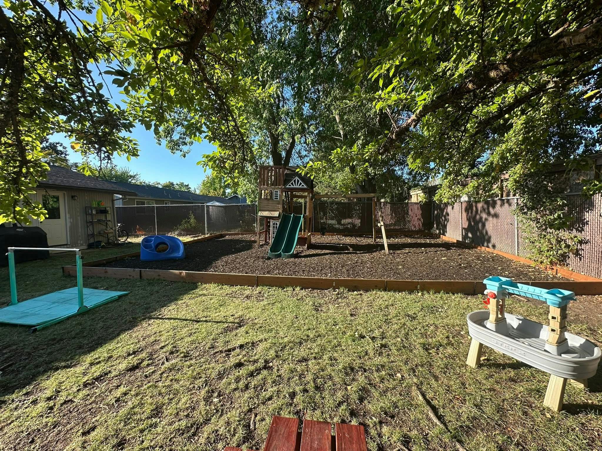 Backyard with a playset, slide, and sandbox