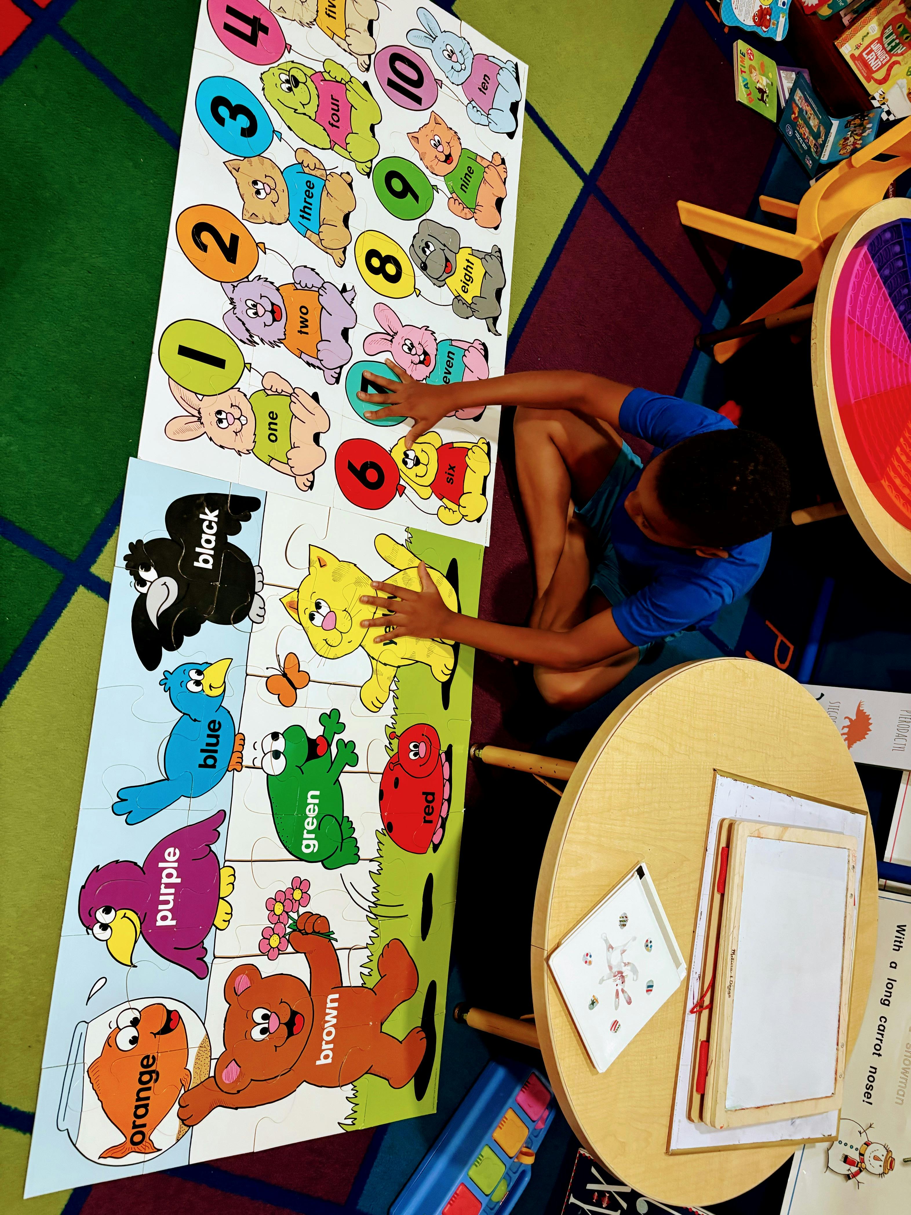 Child playing with large floor puzzles of numbers and colors