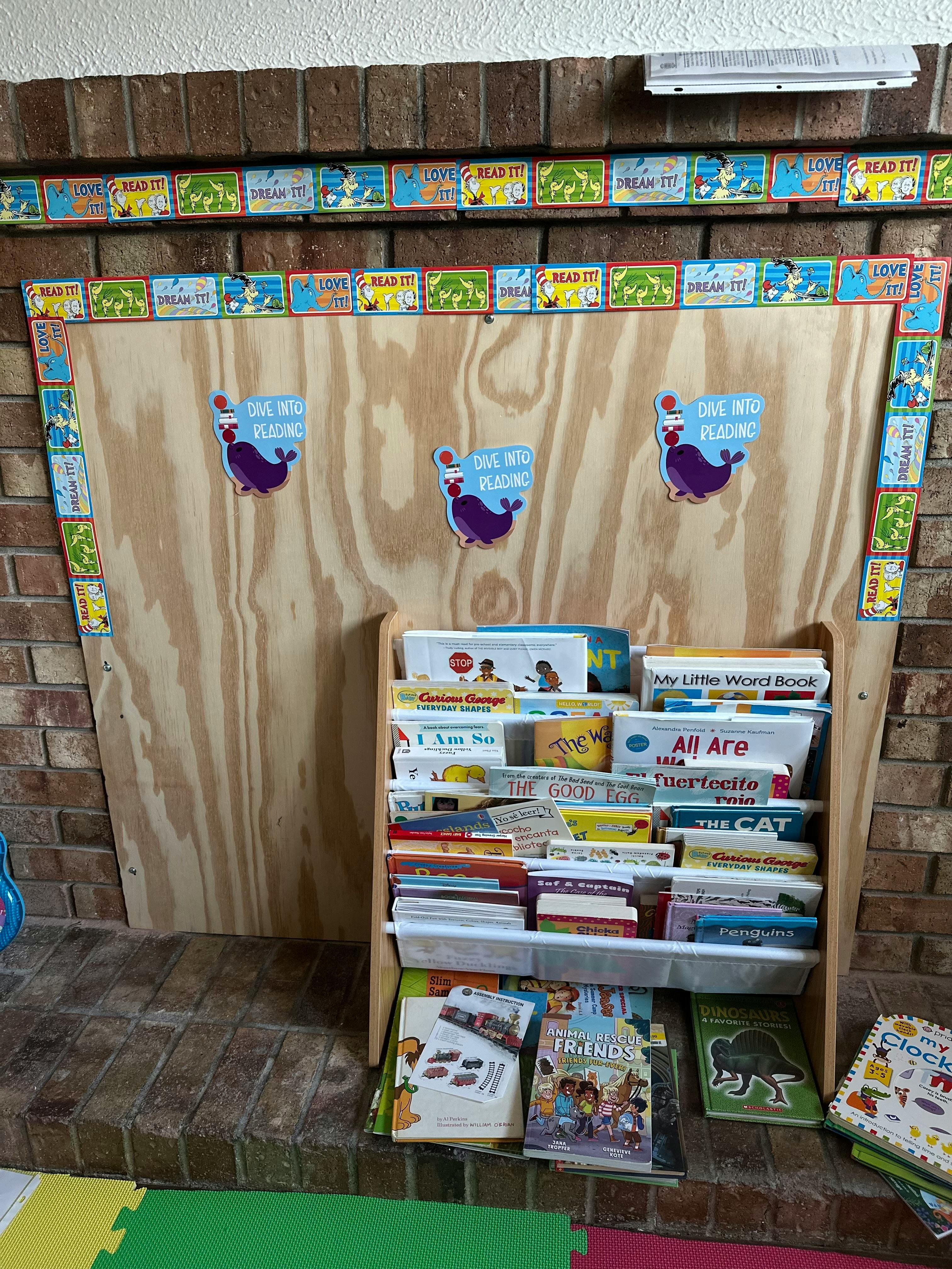 Books on a display rack with Dive into Reading decor on a wooden panel