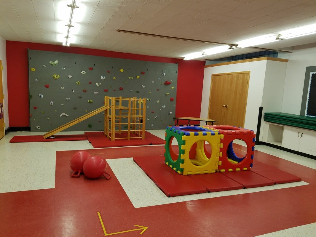 Indoor play area with climbing wall, wooden play structure, and soft play cubes