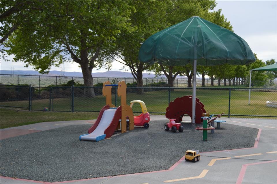 Playground area with small slide, toys, and umbrella