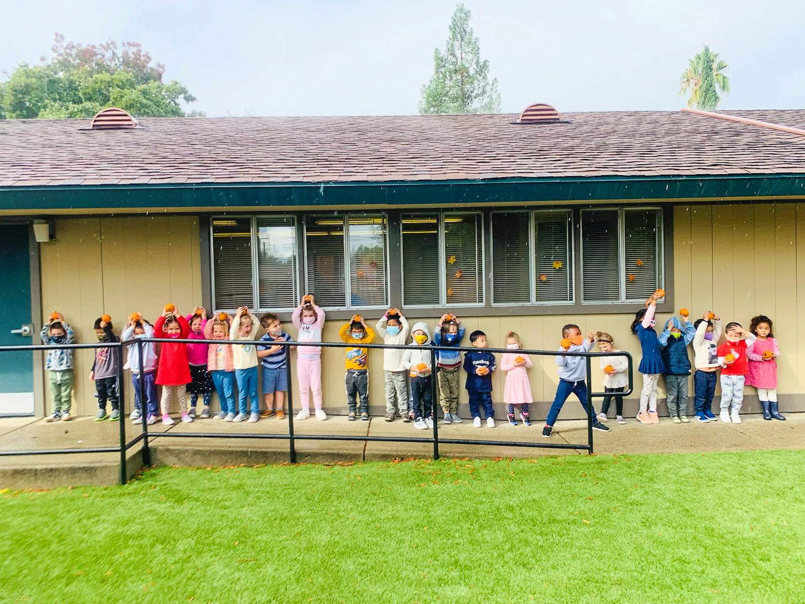 Group of children standing in a line with hands on their heads