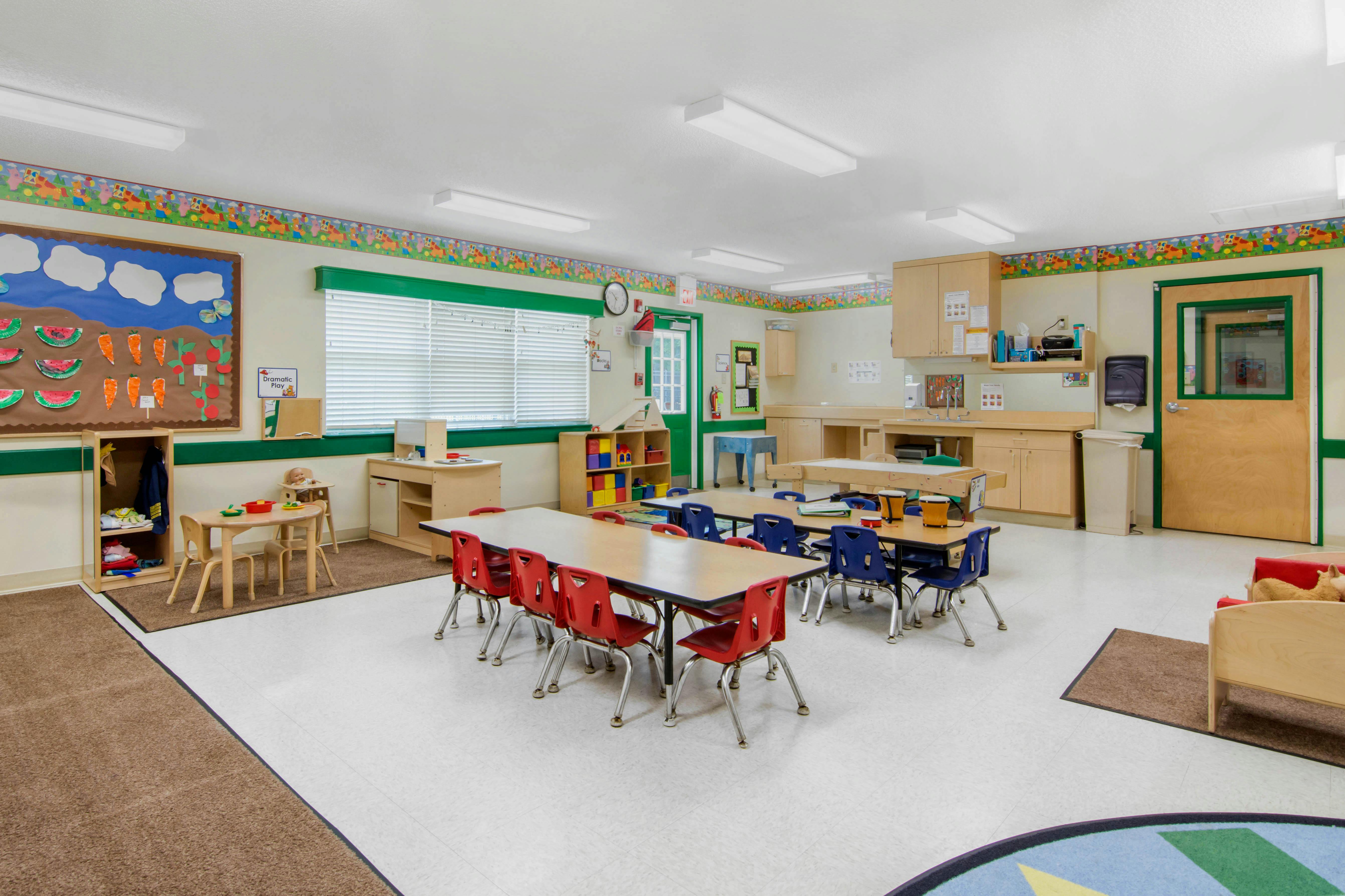 Classroom with child-sized tables and chairs, a sink, and wall decorations
