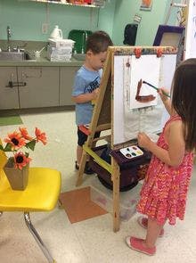 Two children painting at easels in a classroom