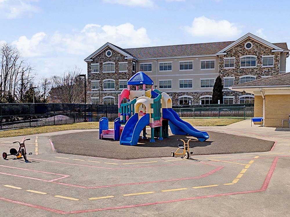 Colorful playground with slides and tricycles on a paved area with painted lines