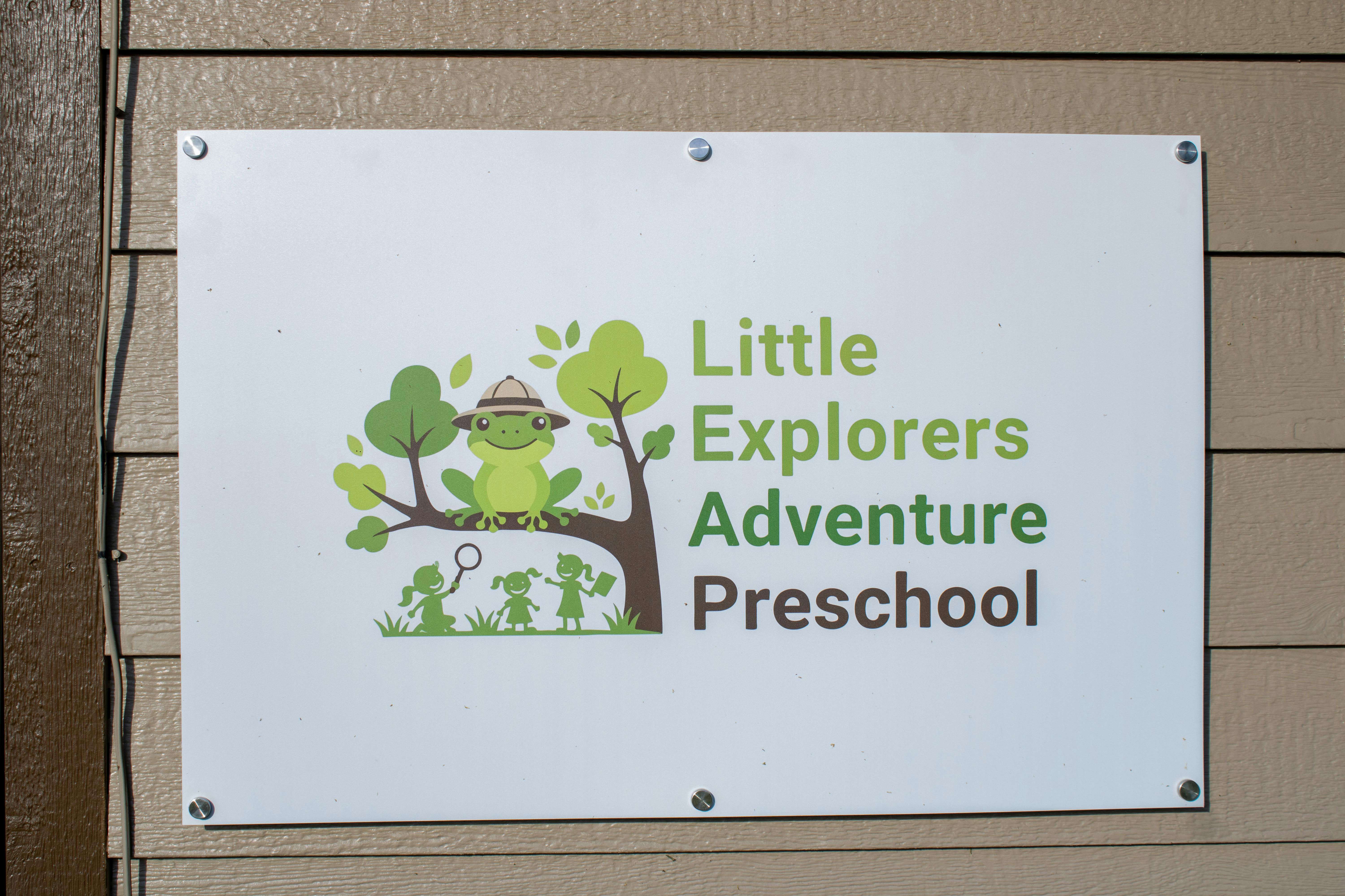 Sign for Little Explorers Adventure Preschool with a frog in a safari hat