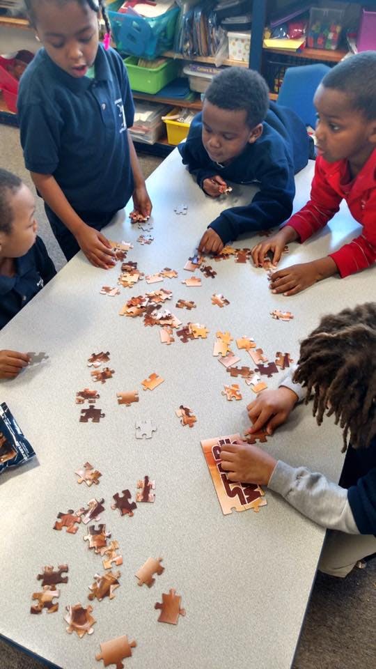 Children working on a puzzle at a table in a classroom
