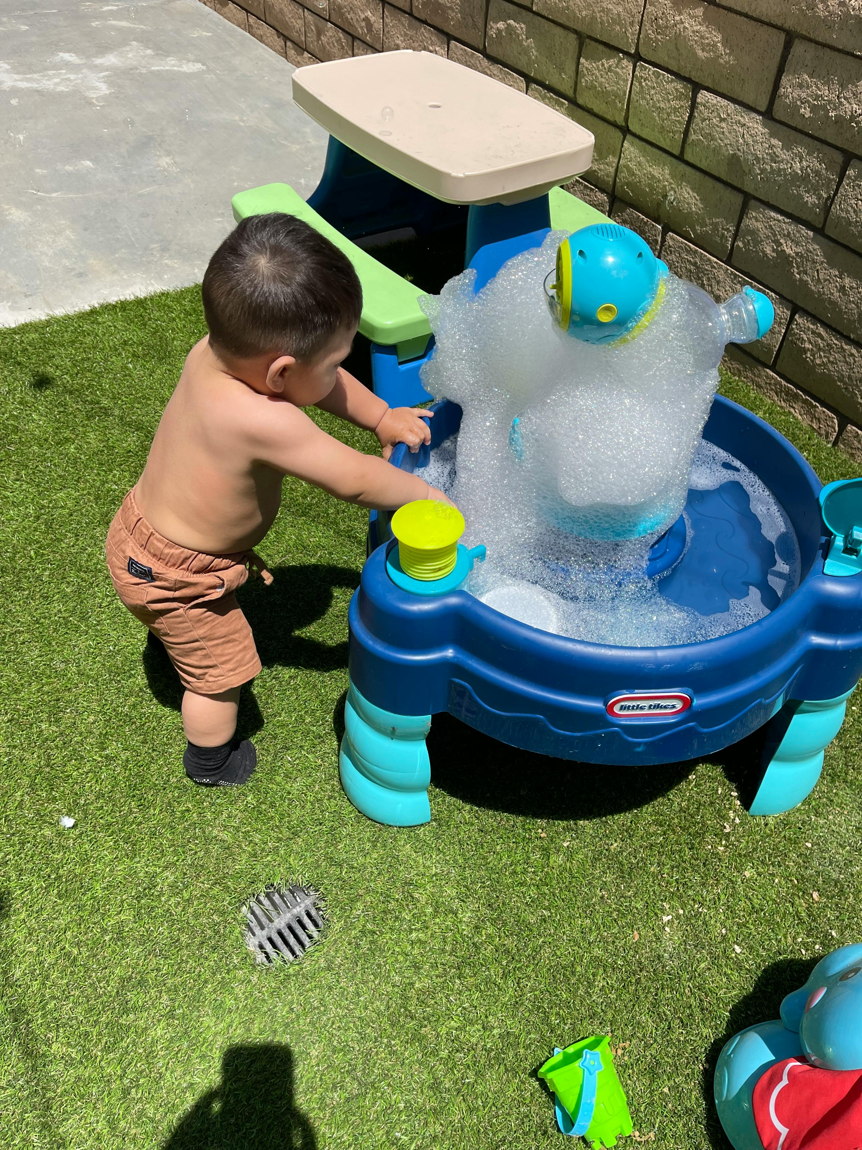 Child playing with a bubble machine on artificial grass