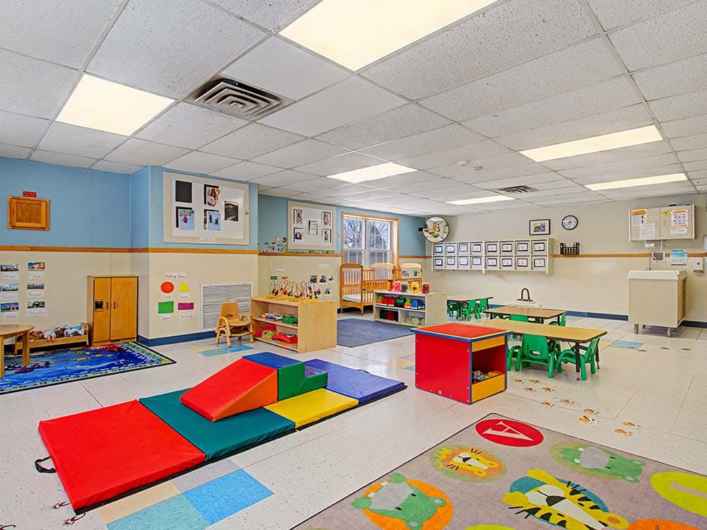 An empty daycare or classroom with colorful play mats and small tables