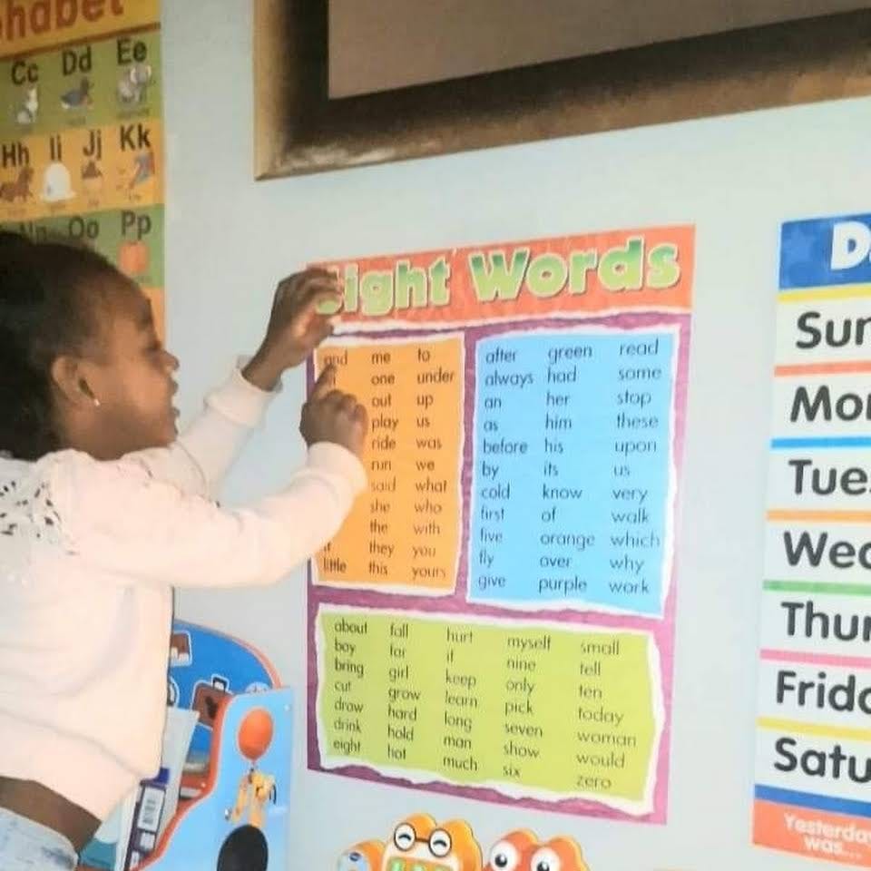 Child pointing at a "Sight Words" chart