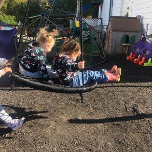 Two children sitting on a swing on a playground