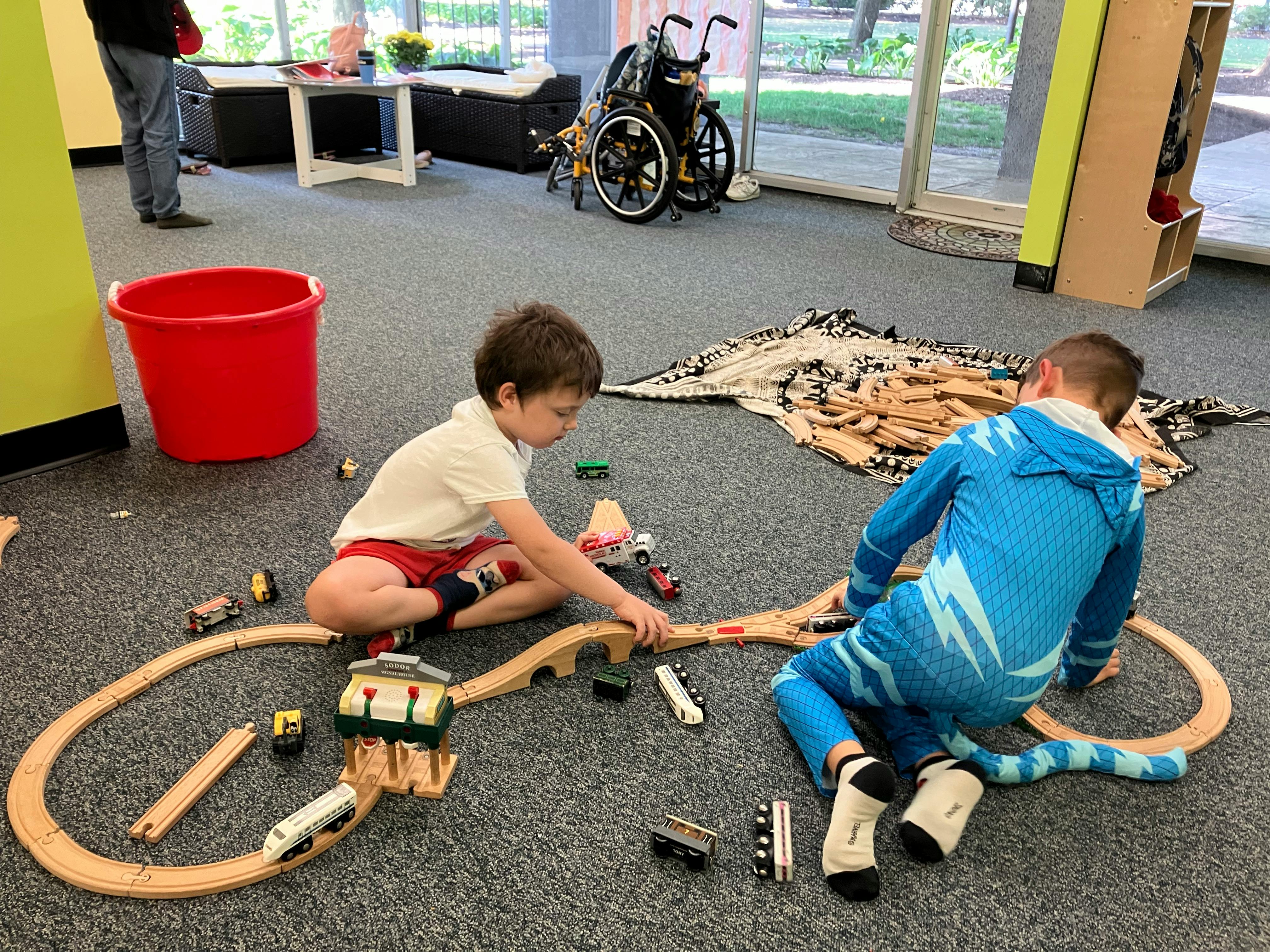 Two children playing with a wooden train set on the floor