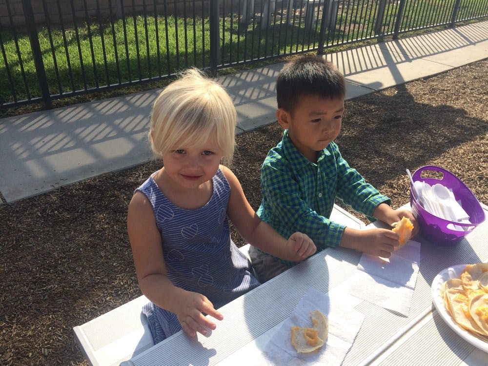 Two children sitting at a table outdoors