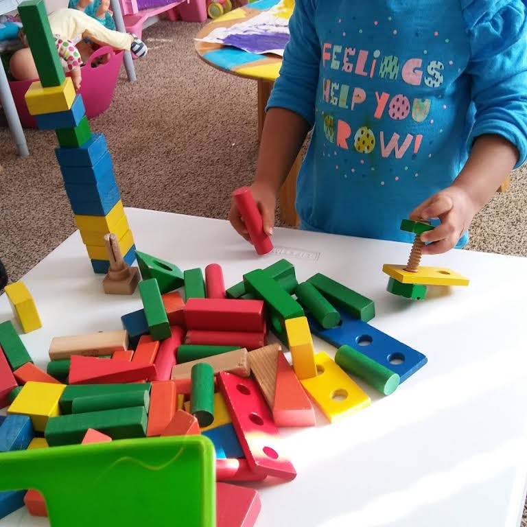 Child playing with colorful wooden blocks on a white table