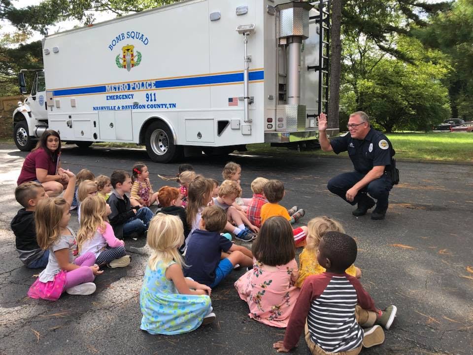 Police officer speaking to a group of children sitting on the ground