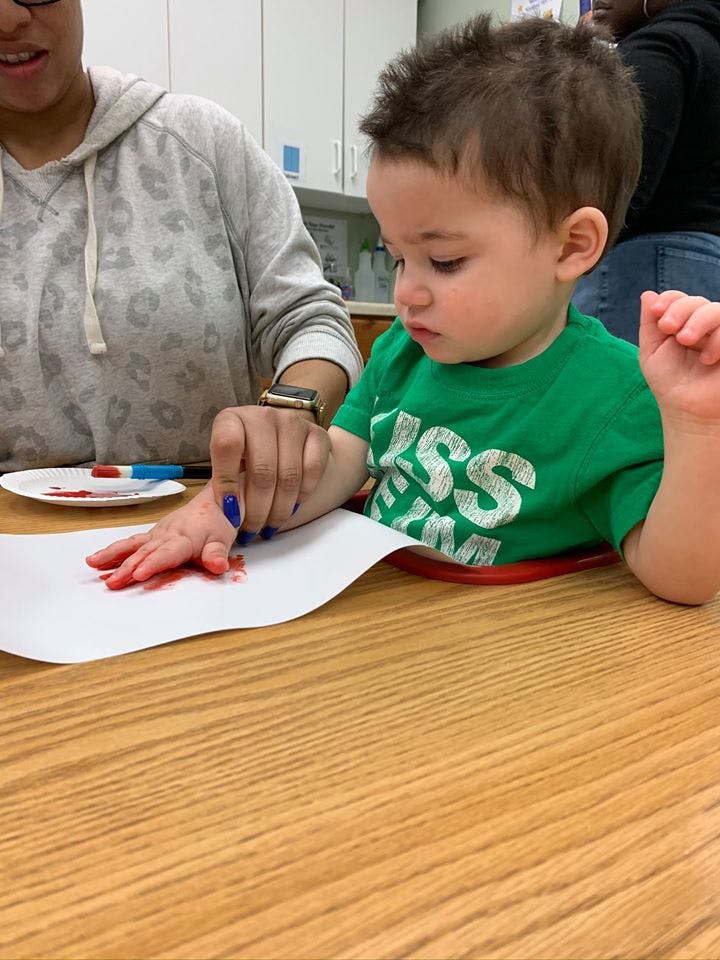 Person helping a child with finger painting