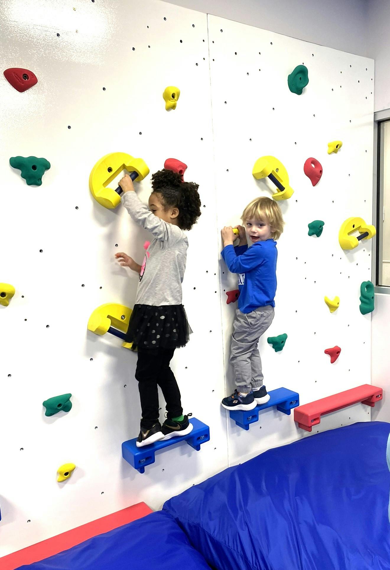 Two children climbing on an indoor rock wall