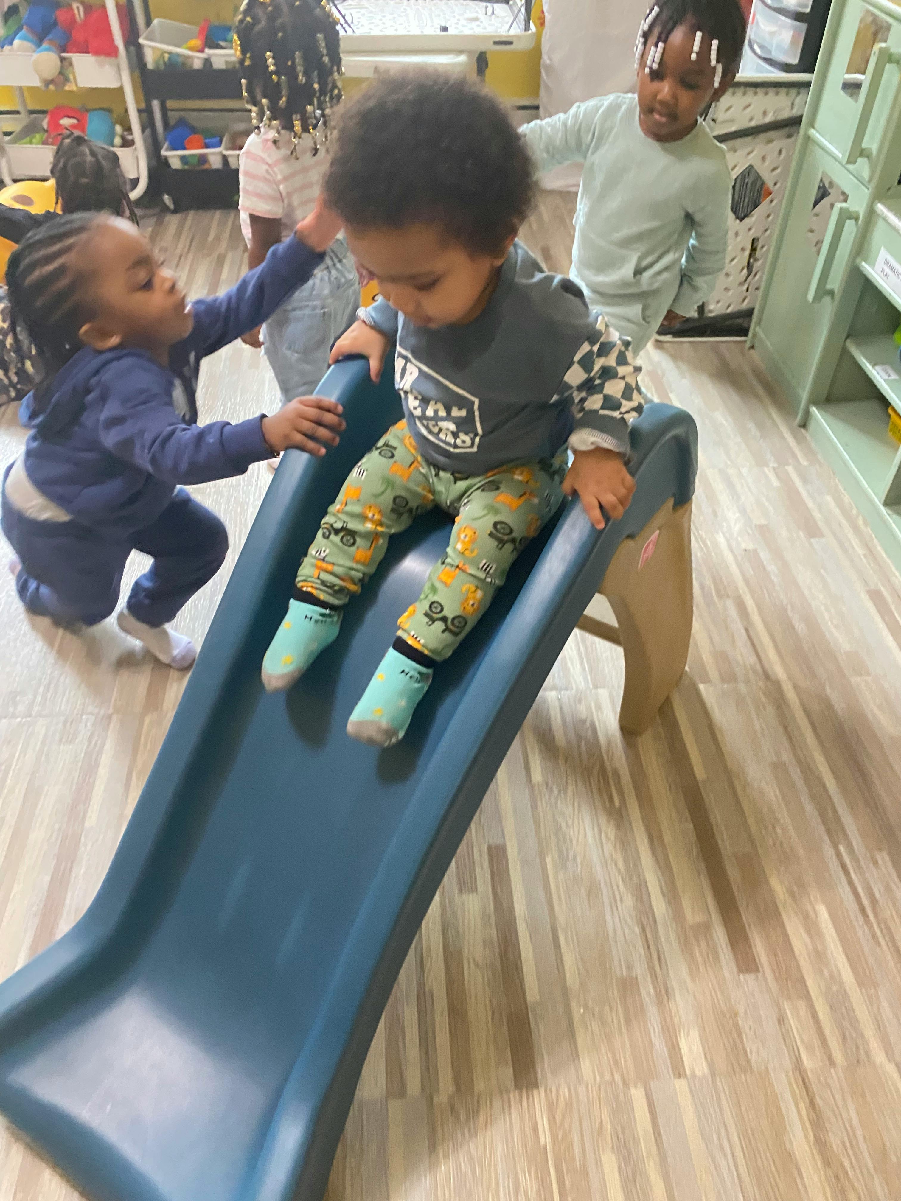 Child on a slide with another child nearby