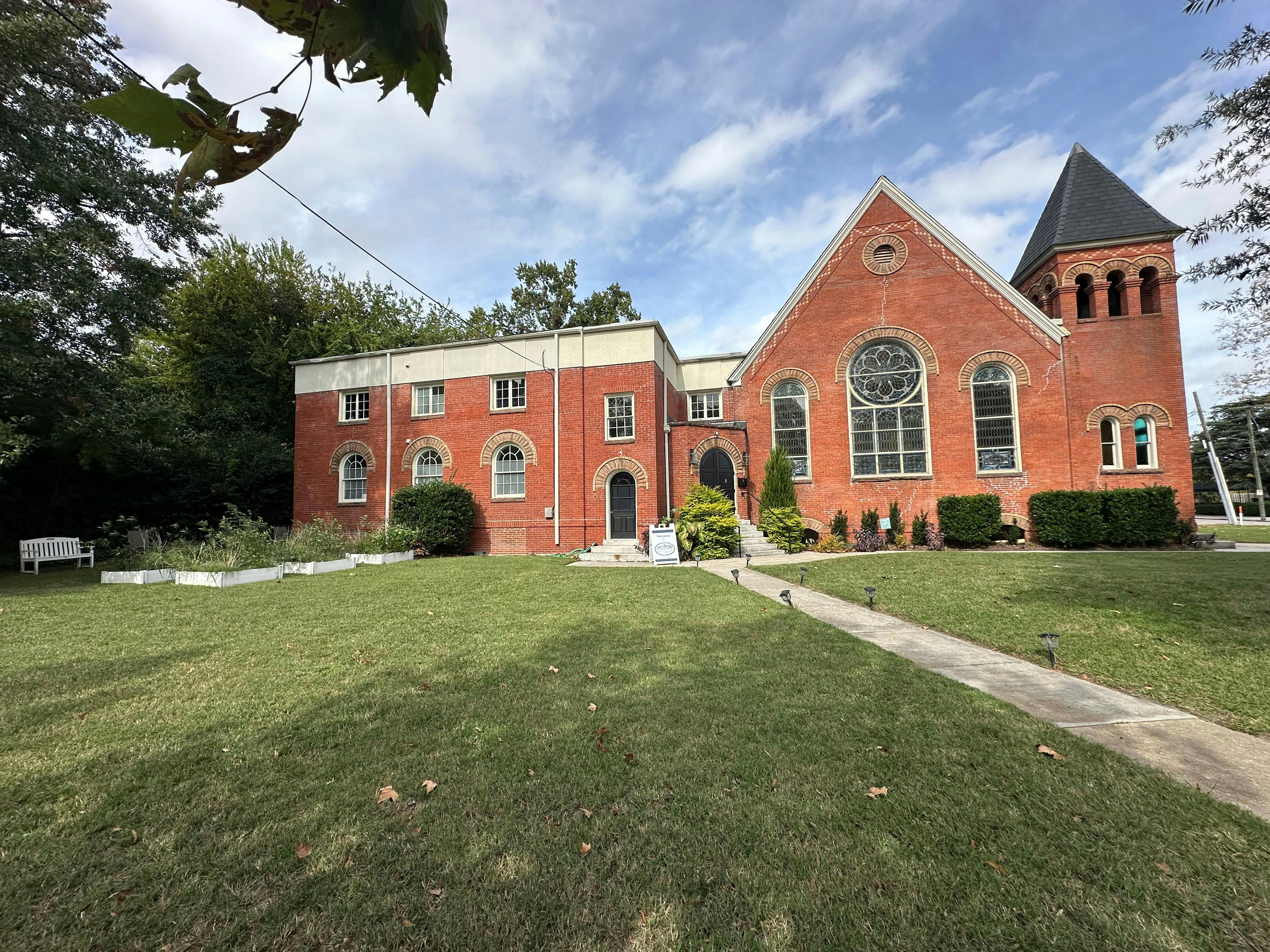 Red brick building with a tall steeple and a large arched window