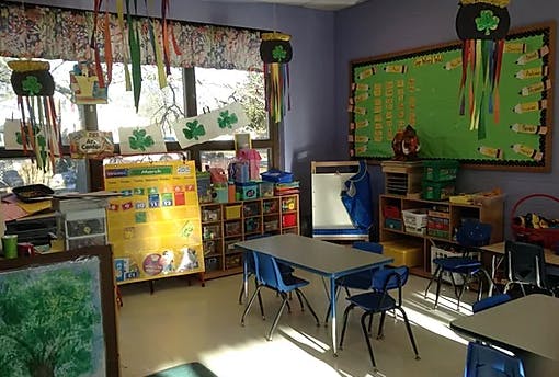 Classroom with tables, chairs, and a green bulletin board
