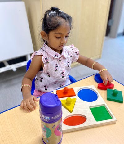Child playing with a shape sorter puzzle at a table