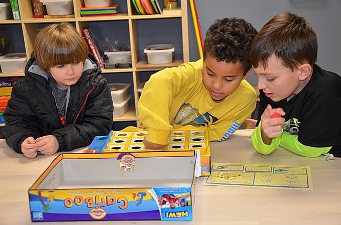 Three children playing a board game at a table