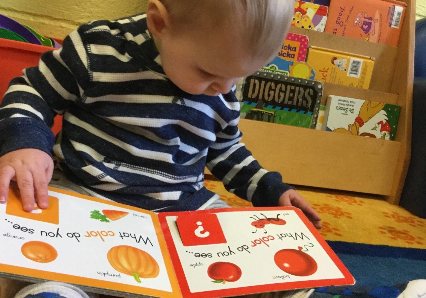 Child looking down at an open book with illustrations