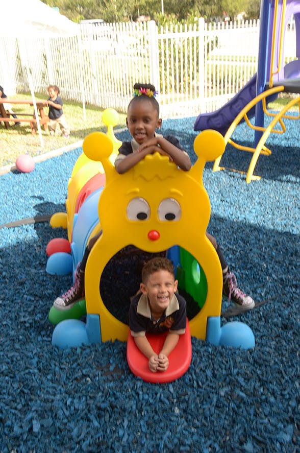 Two children playing on a caterpillar-shaped playground tunnel