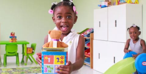 Child holding a toy with a teddy bear on top