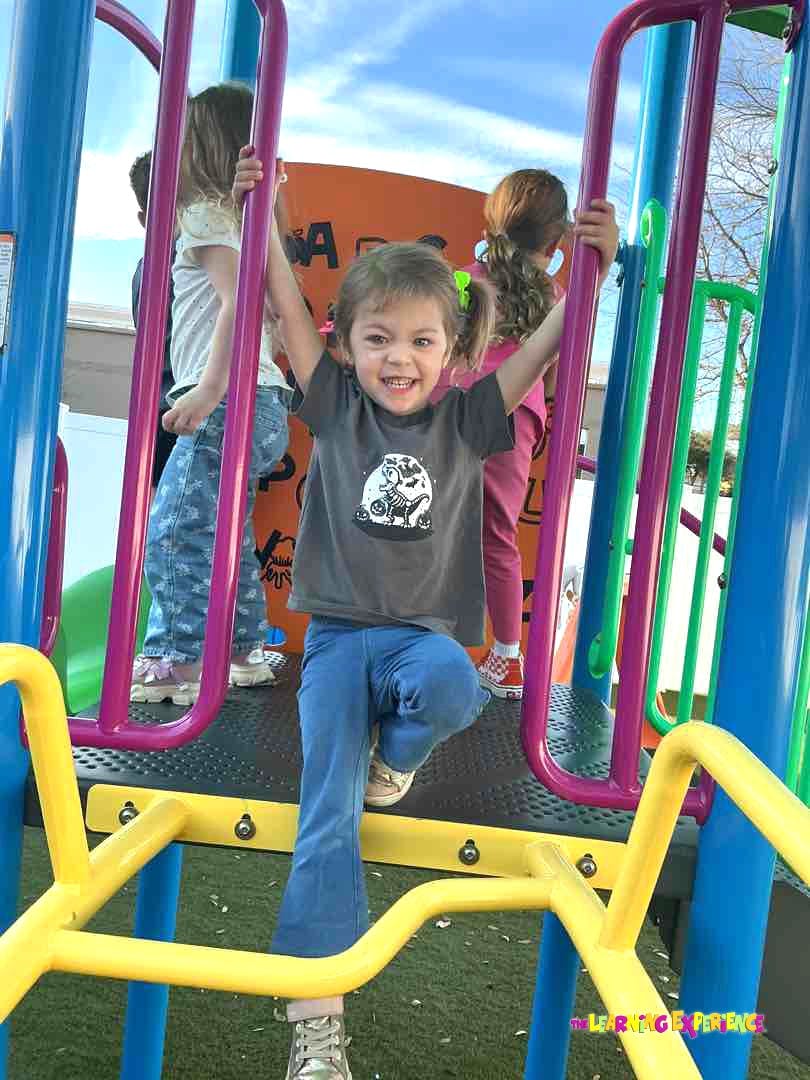 Child on a playground structure with other children in the background