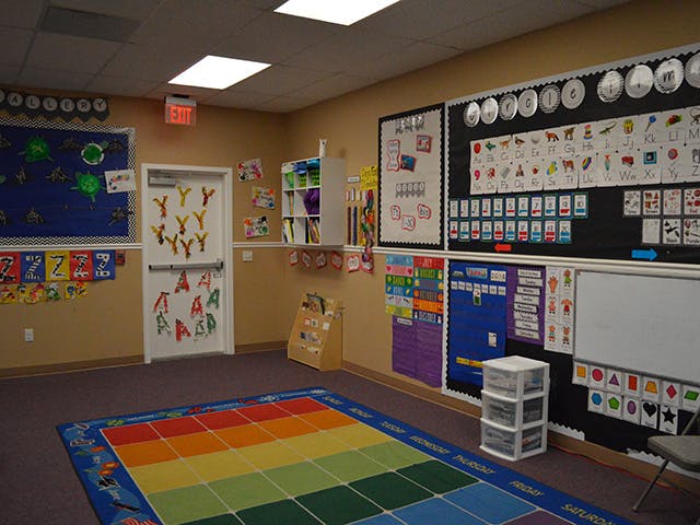 Empty classroom with a colorful rug and educational posters on the walls