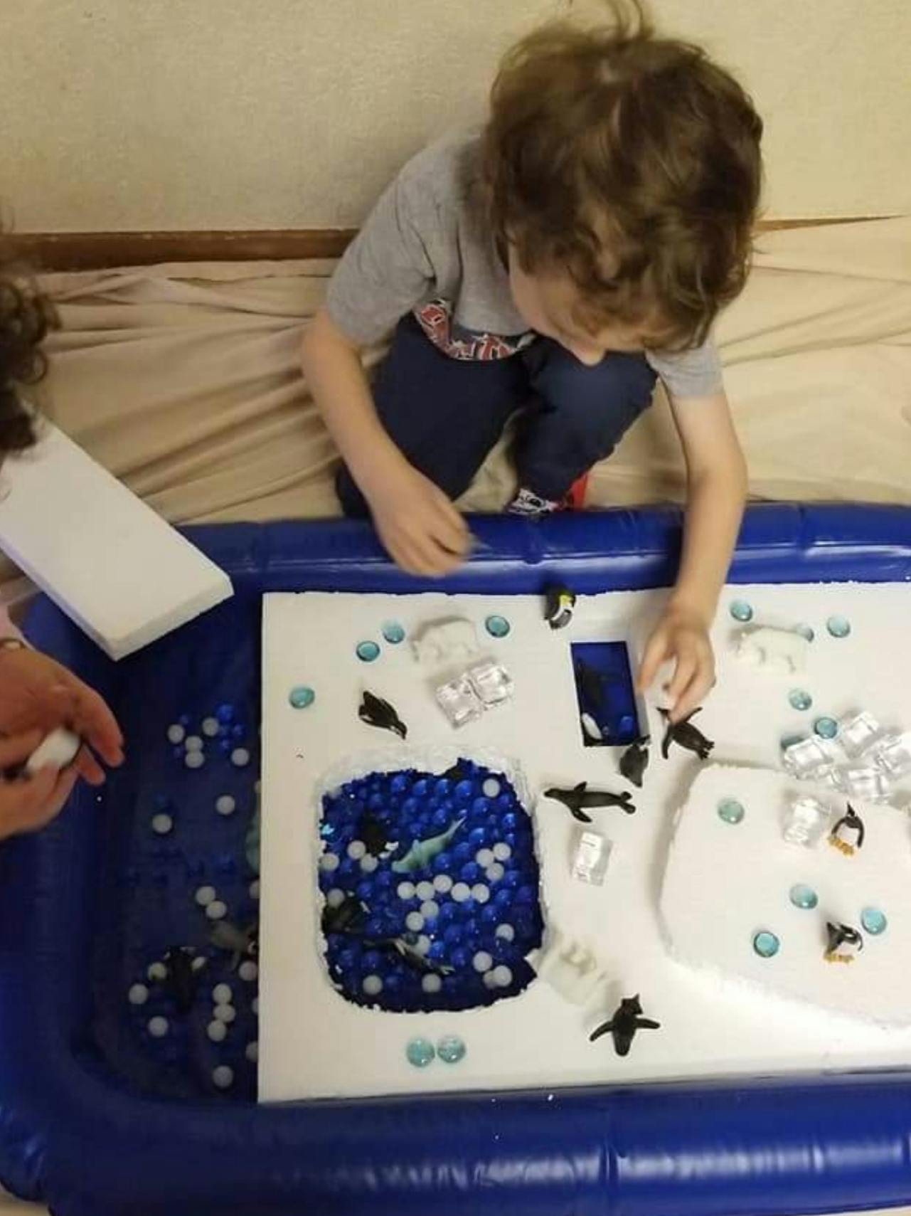 Child playing with arctic animal figurines in a sensory bin