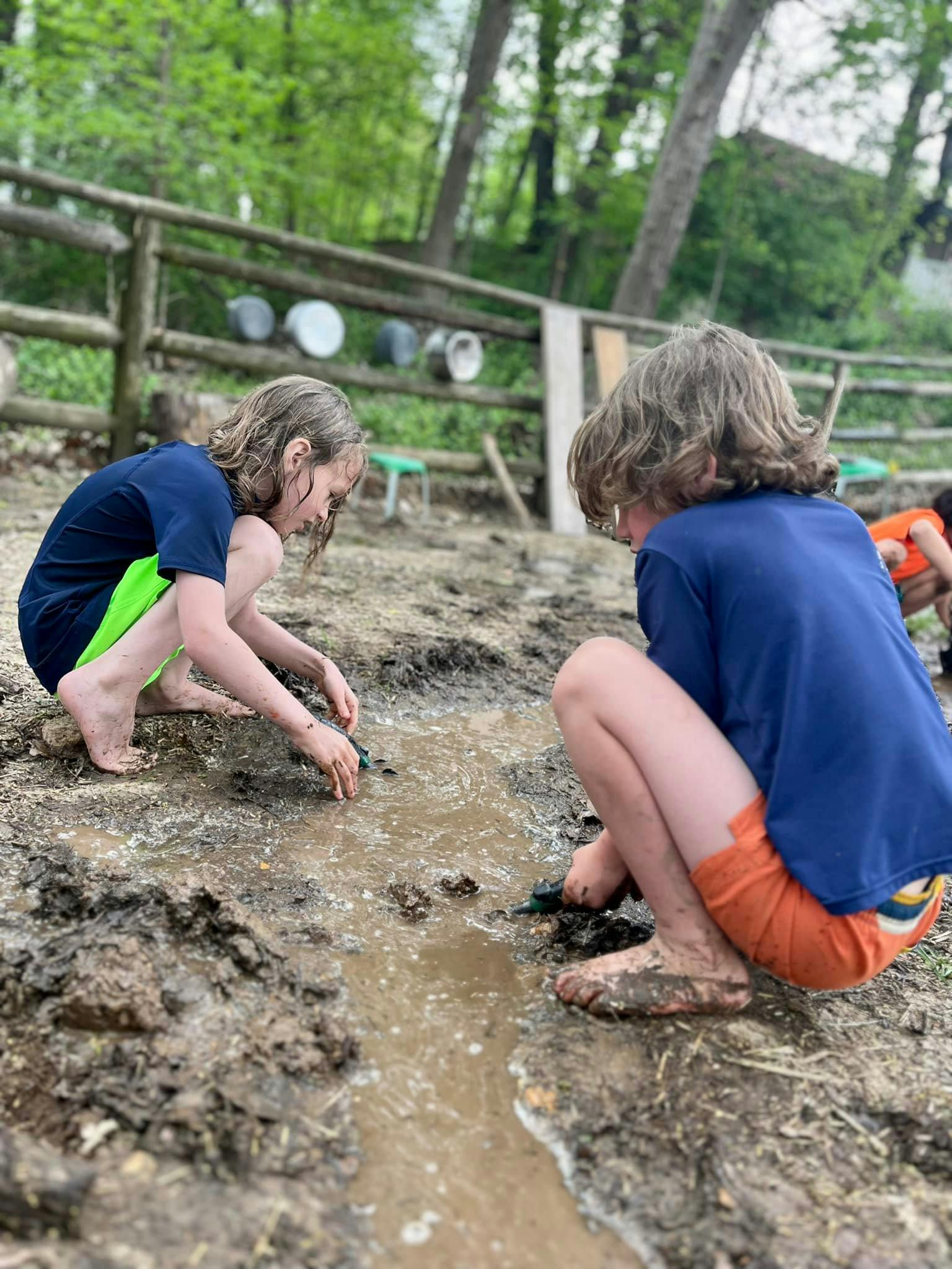 Two children playing in mud and water outdoors