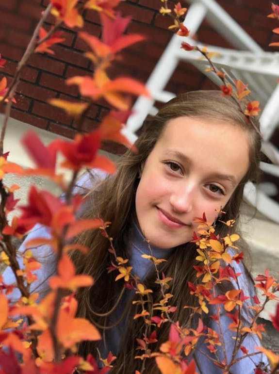 Teen looking through autumn leaves