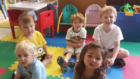Five children sitting on a colorful mat