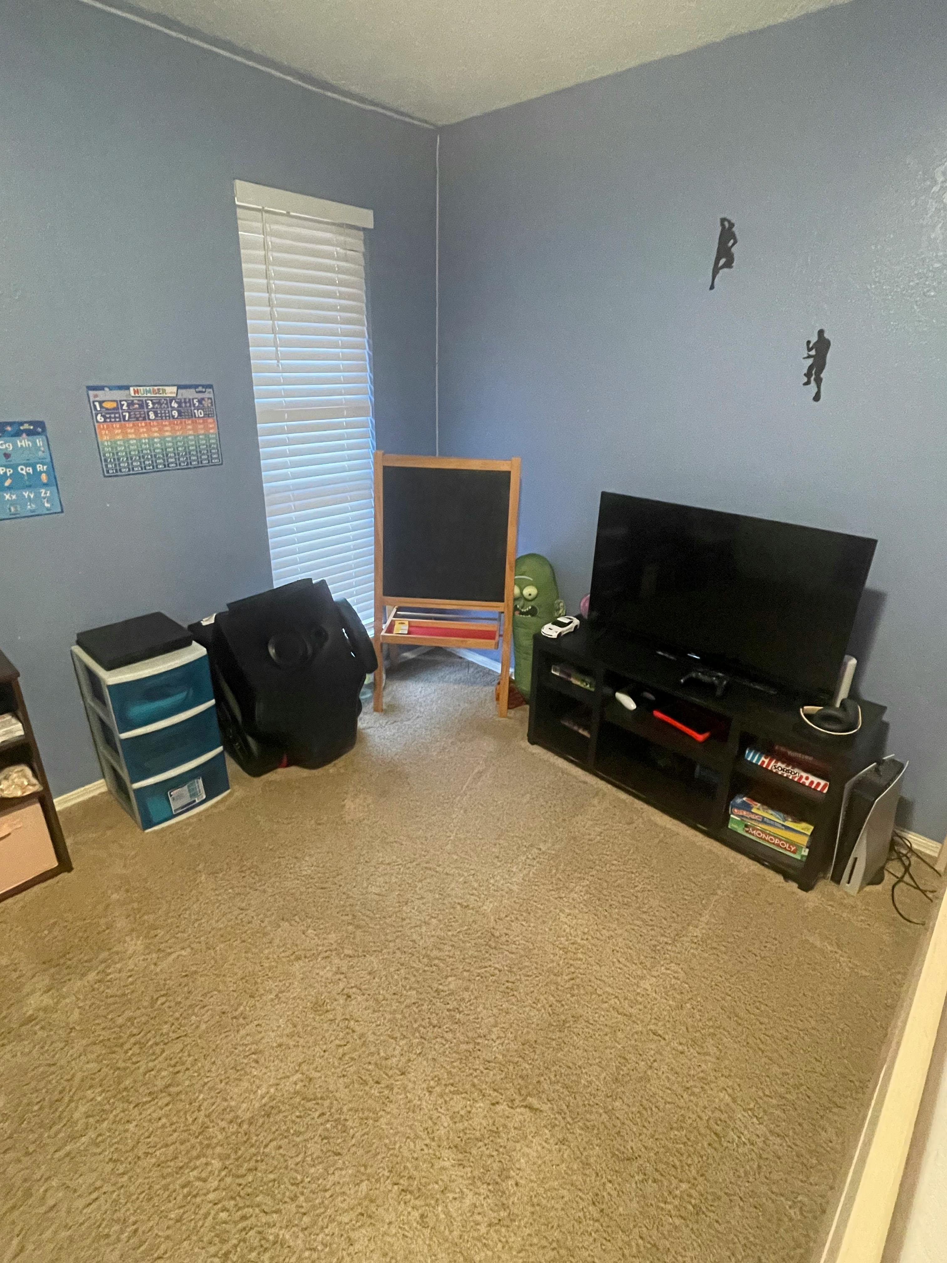 Room with a television, media console, chalkboard, and storage drawers