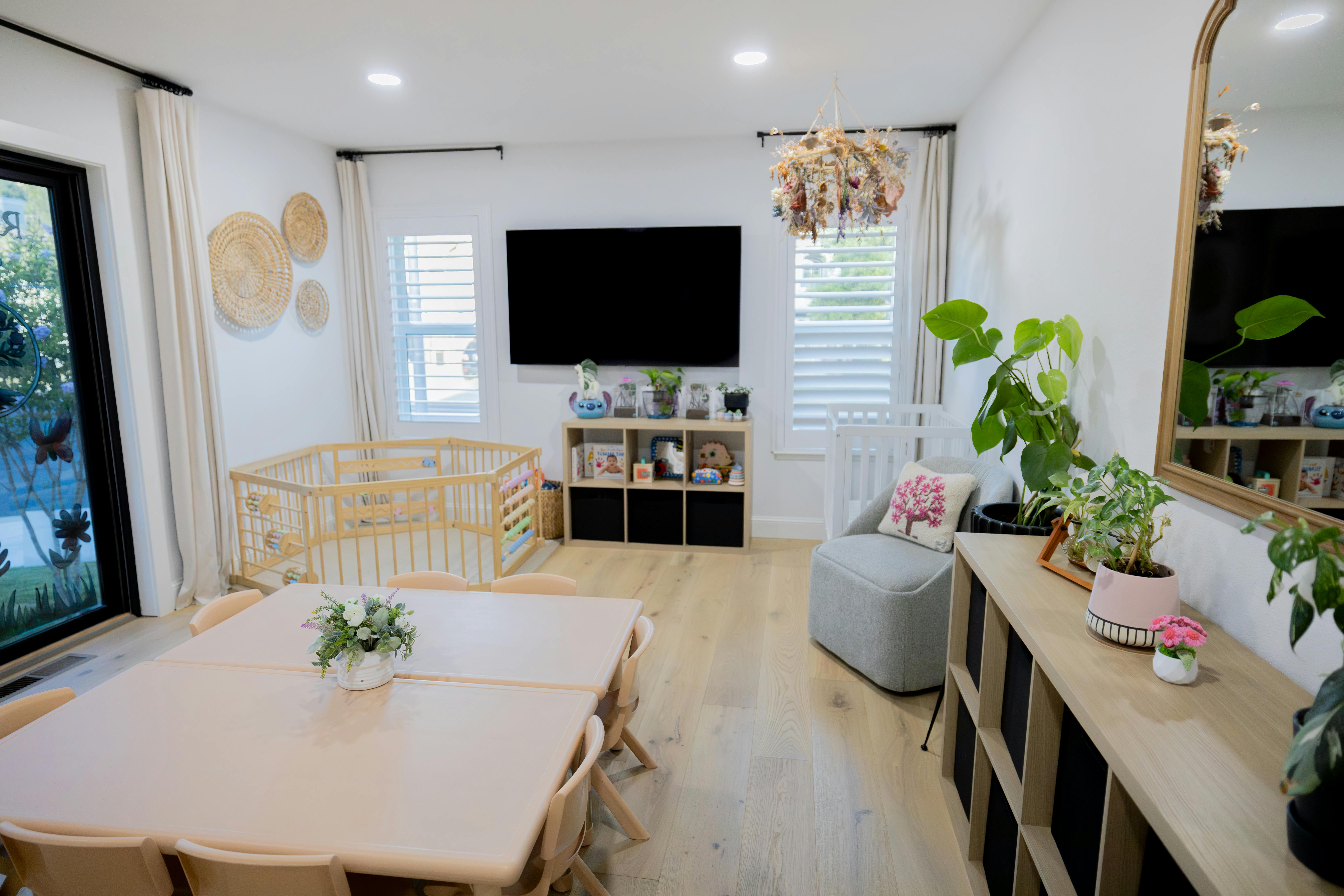 Child playroom with table and chairs, playpen, shelves, and armchair