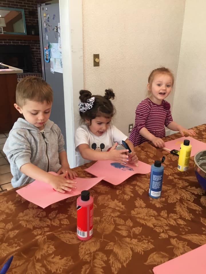 Three children doing crafts with paint and paper