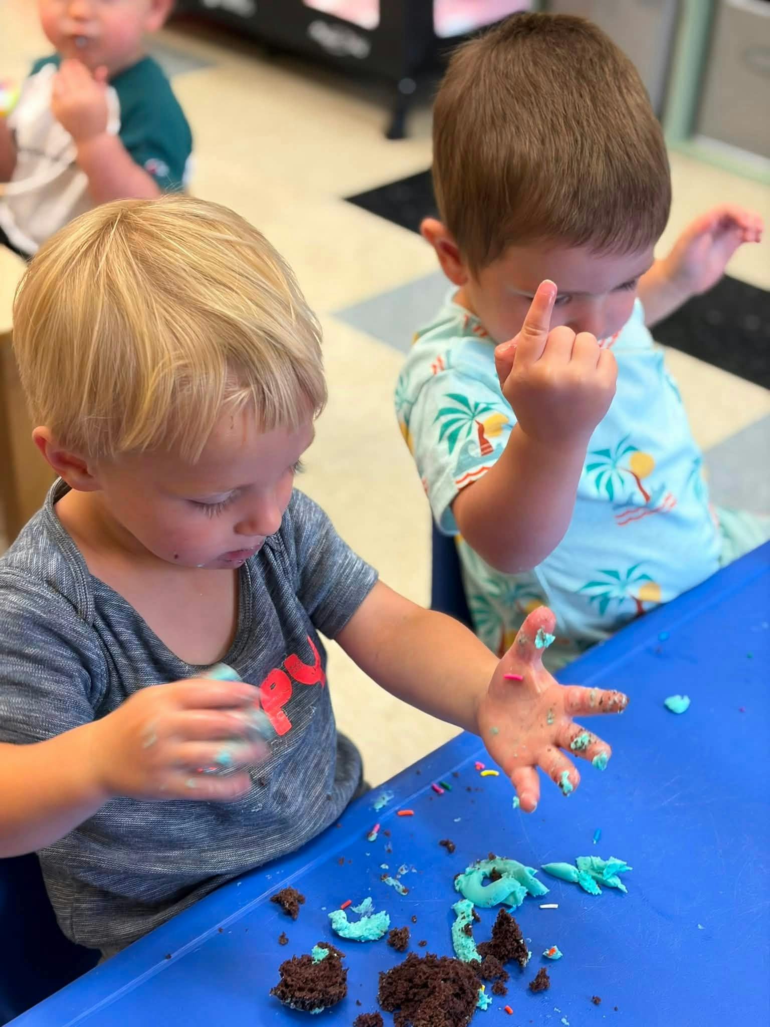 Children playing with cake and blue frosting at a table