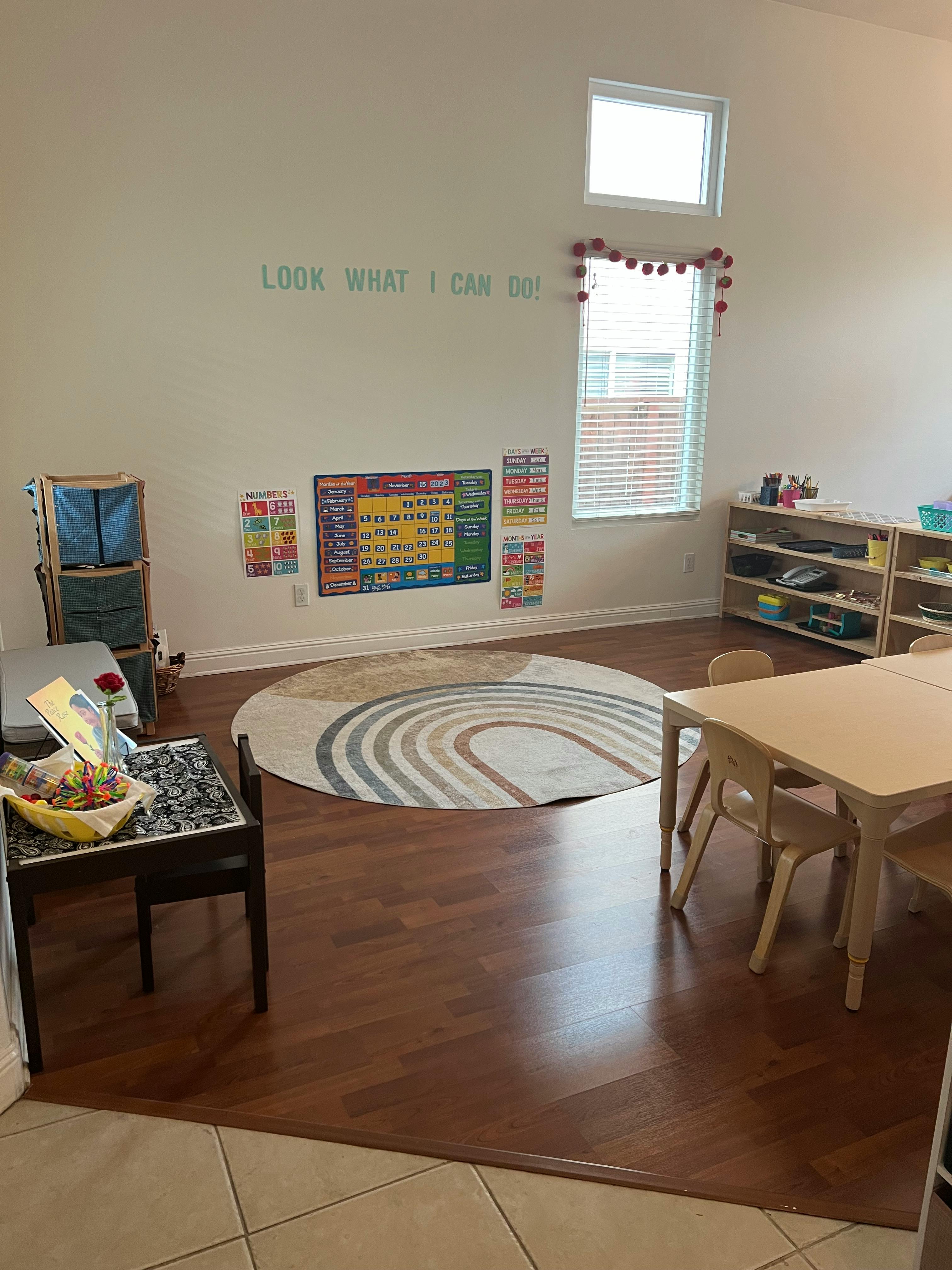 Classroom with a round rug, small table and chairs, and educational posters