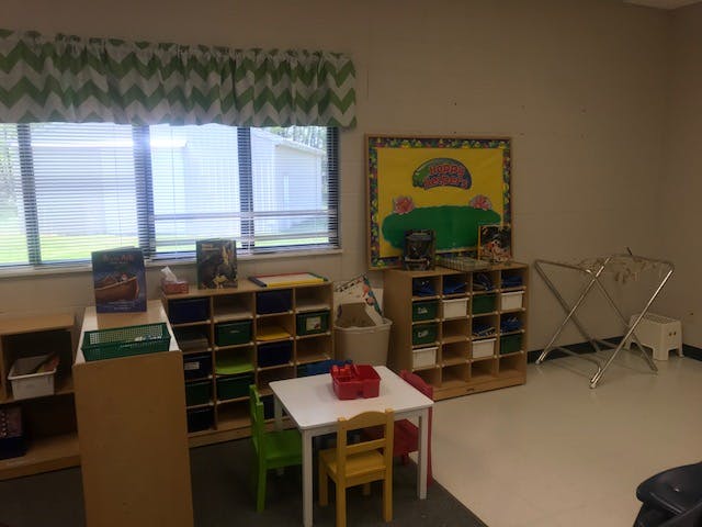 Classroom with small tables and chairs, storage cubbies, and a window