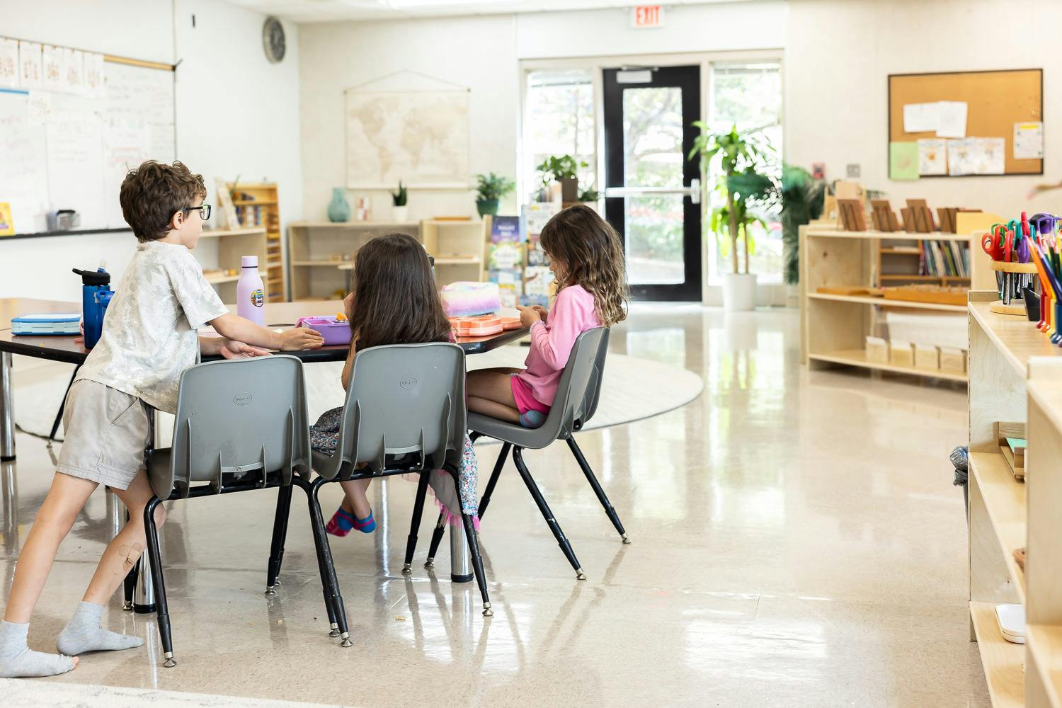 Three children sitting at a table in a classroom