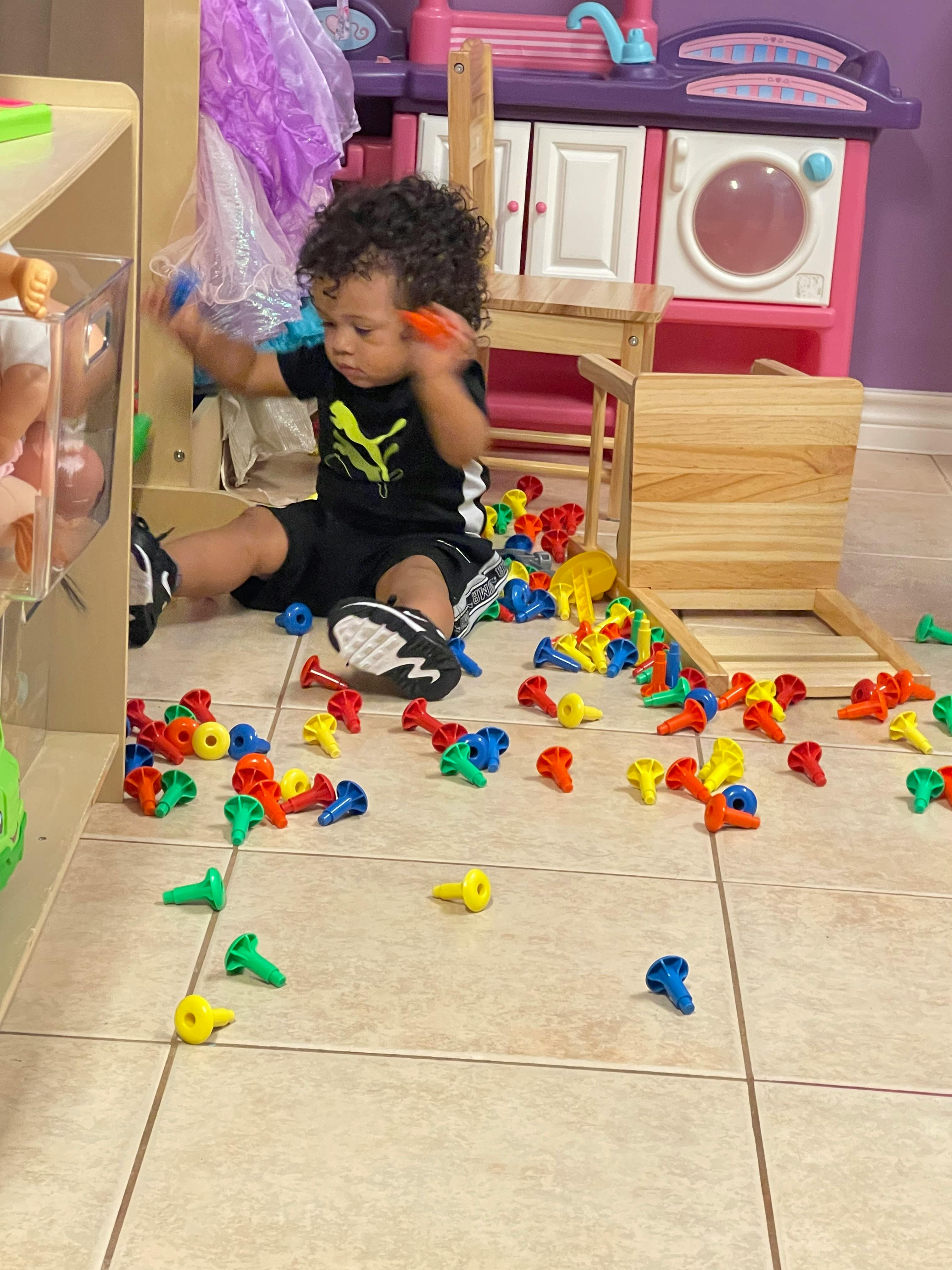Child sitting on the floor playing with colorful plastic pegs