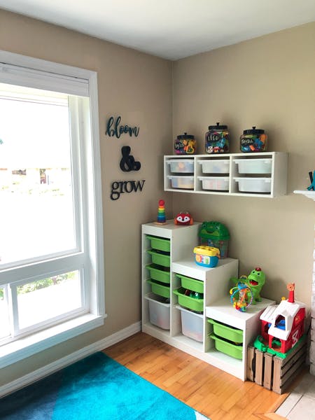 Playroom with toy storage shelves, wall decor, and a window