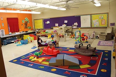 Playroom with a colorful rug, toys, and child-sized furniture
